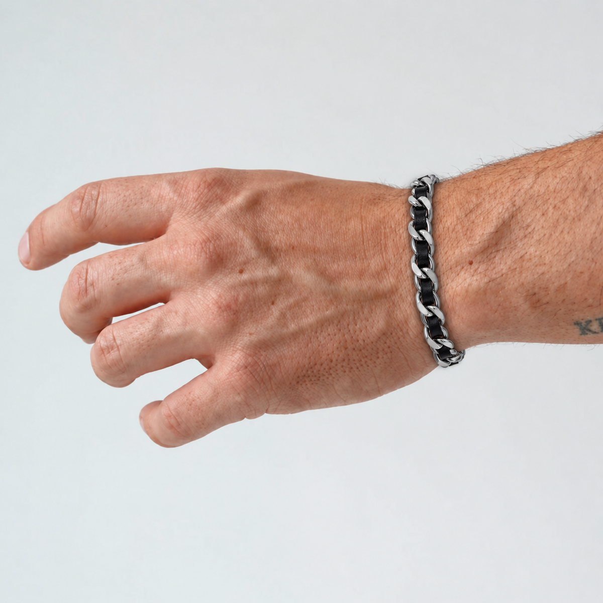 Close-up of Cuban Leather Bracelet on wrist showing its black leather band and polished metal accents
