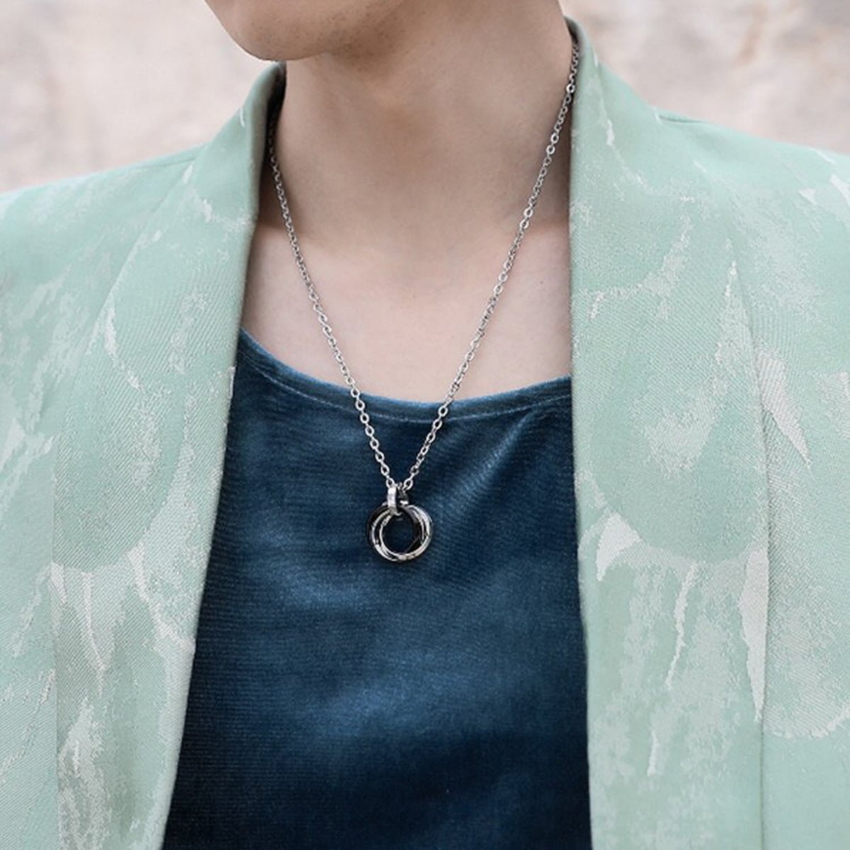 Men's Interlocking Ring Necklace styled with a dark shirt and mint green jacket