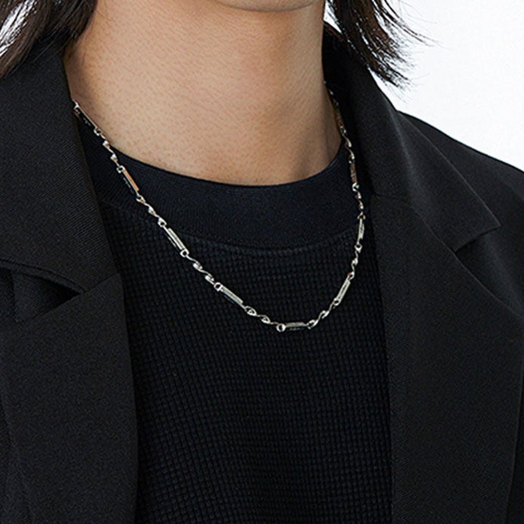 Men's Mobius Link Necklace styled with a black blazer and dark shirt for a modern minimalist look